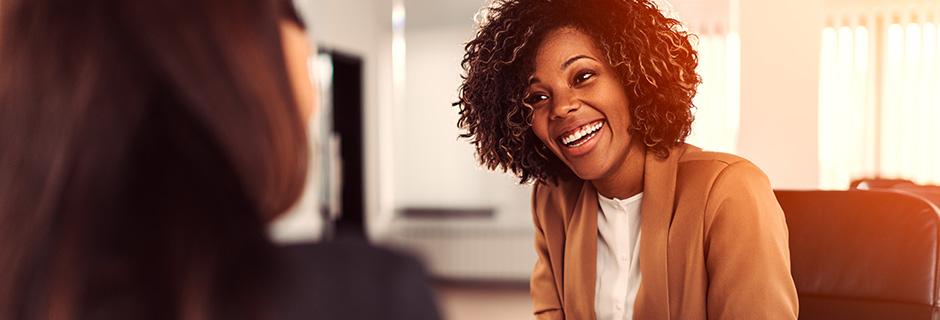 AI image of a woman in a suite (presumably an HR employee) smiling at someone she is working with in an office. 