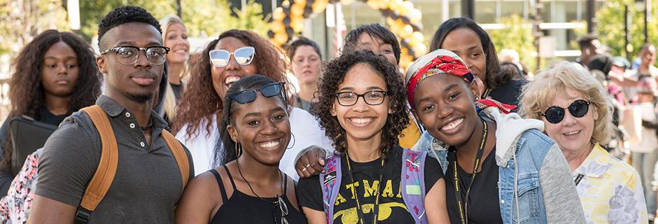 Group of students in a crowd outside, all smiling at the camera.