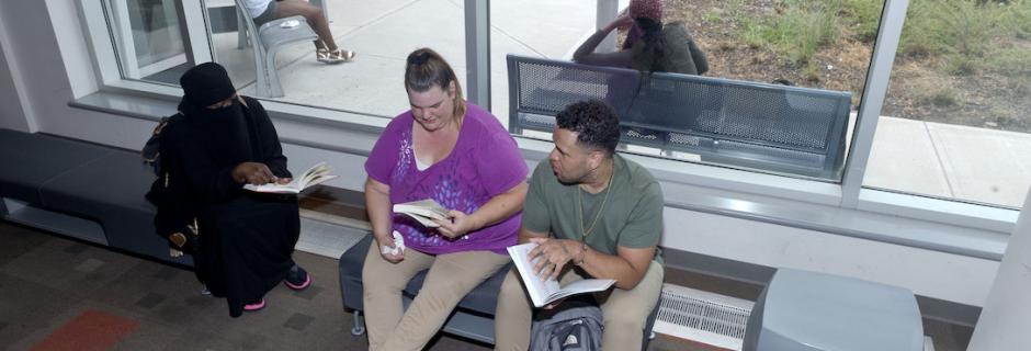 Students sitting an talking in the lobby of a building on main campus.